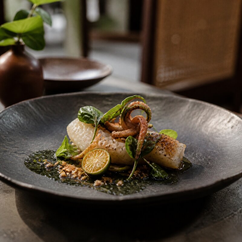 An elegant contemporary Filipino tasting-menu plate on dark handmade ceramic